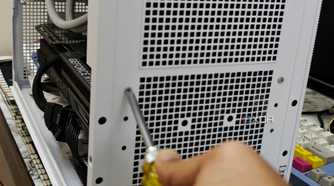 An image showing a person undoing the screws holding the PSU on the case.