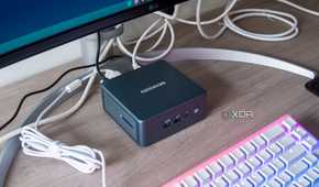 Geekom Mini IT13 mini PC under a monitor with a keyboard in front of it