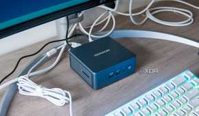 Geekom Mini IT13 mini PC under a monitor with a keyboard in front of it