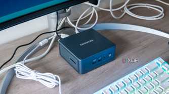 Geekom Mini IT13 mini PC under a monitor with a keyboard in front of it