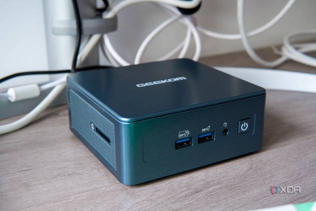 Angled front view of the Geekom Mini IT13 in front of a monitor