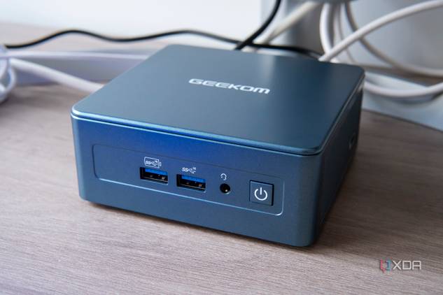 Angled front view of the Geekom Mini IT13 in front of a monitor