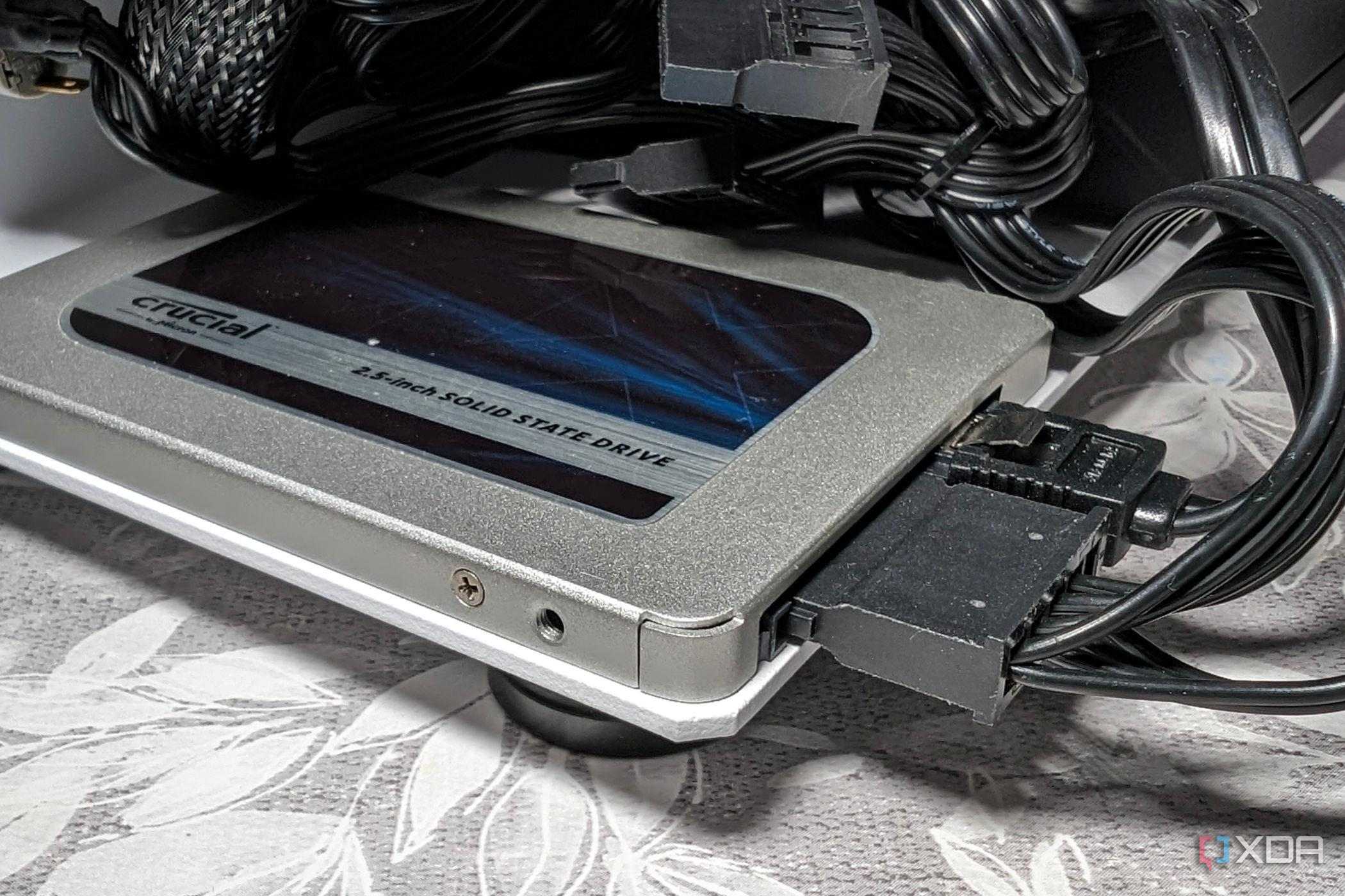 An image featuring crucial bx500 sata ssd drive behind what appears to be a bunch of wires tangled together.