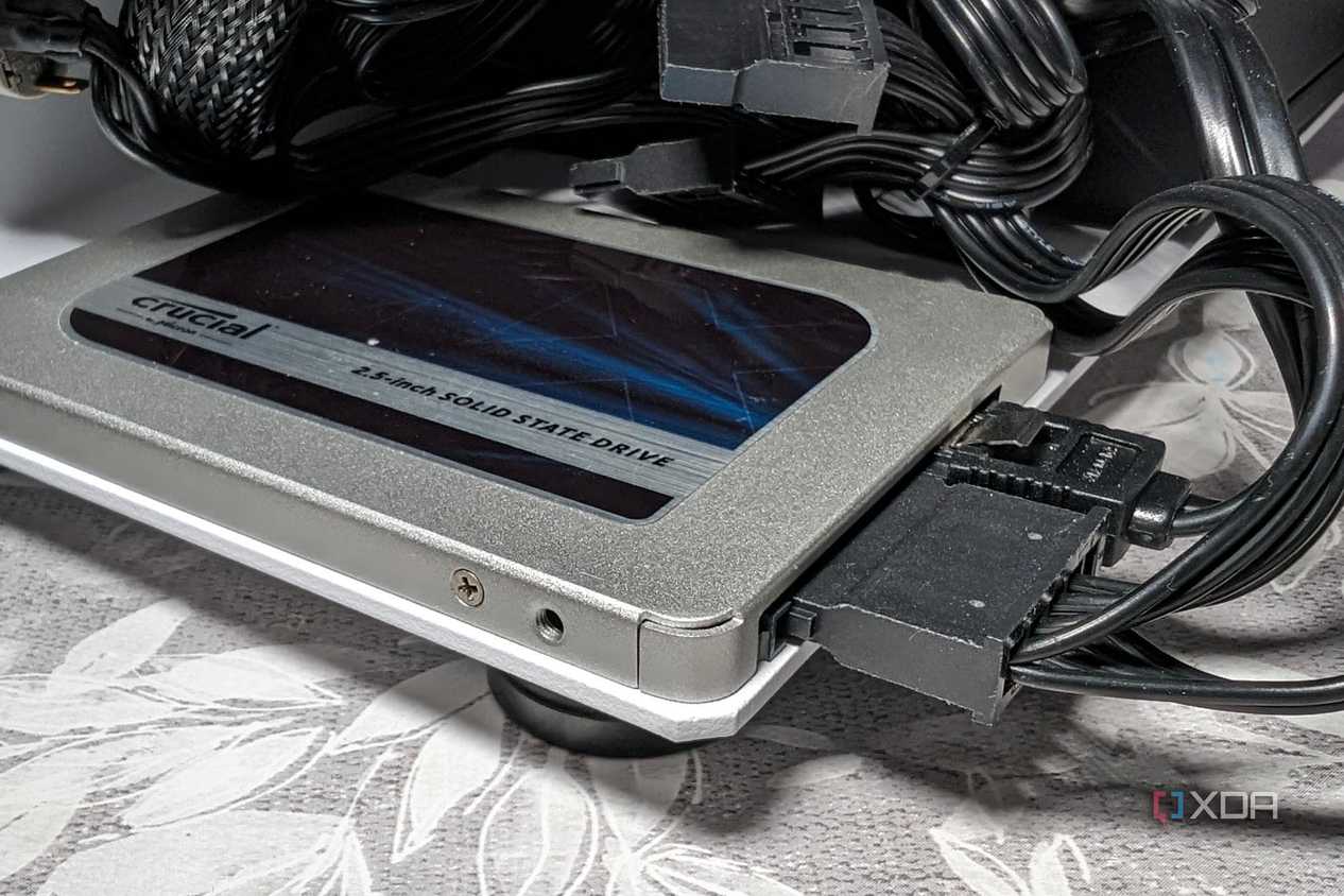 An image featuring crucial bx500 sata ssd drive behind what appears to be a bunch of wires tangled together.