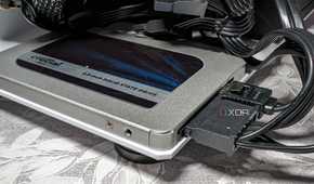 An image featuring crucial bx500 sata ssd drive behind what appears to be a bunch of wires tangled together.