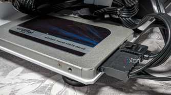 An image featuring crucial bx500 sata ssd drive behind what appears to be a bunch of wires tangled together.