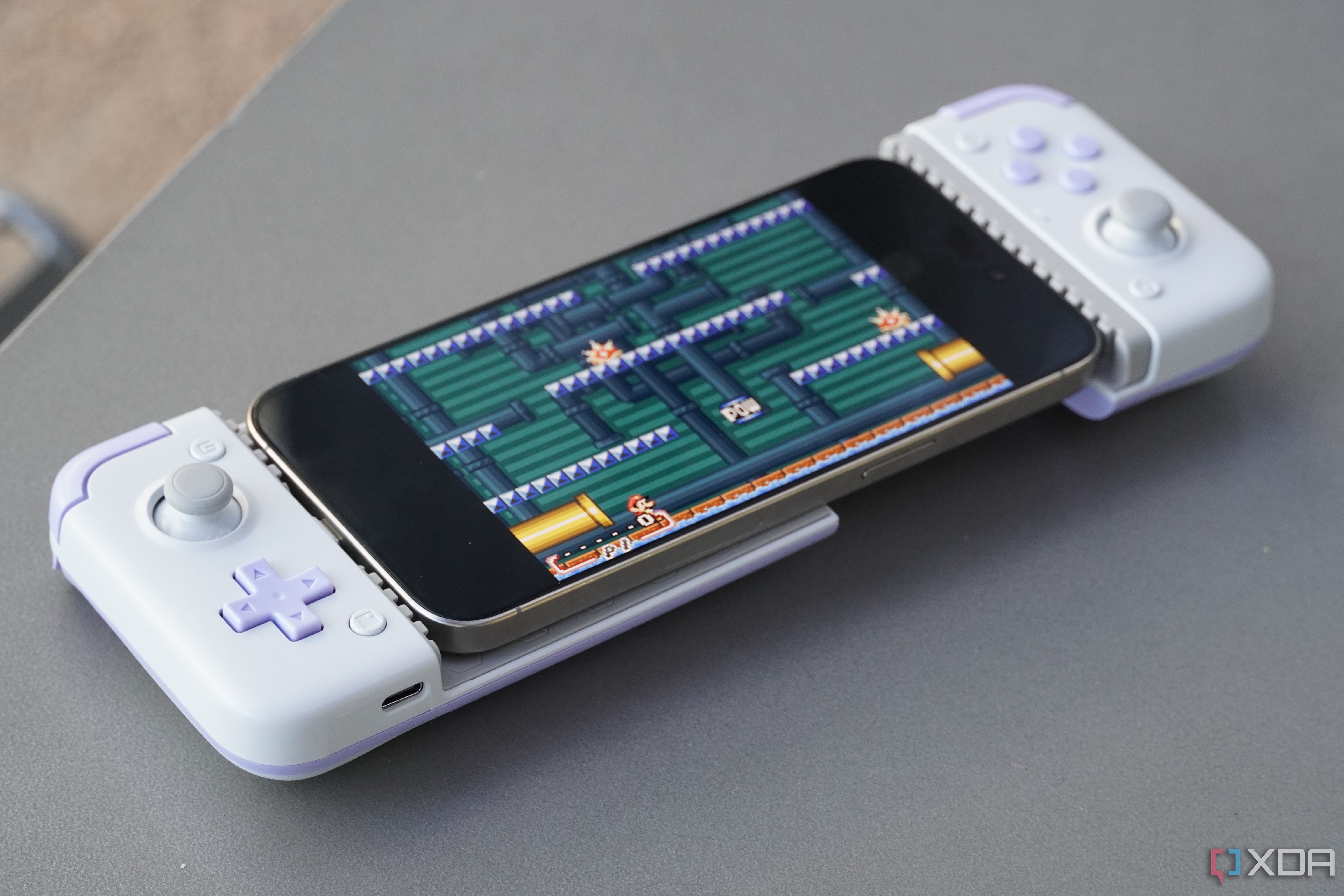 An iPhone connected to a mobile gaming controller.