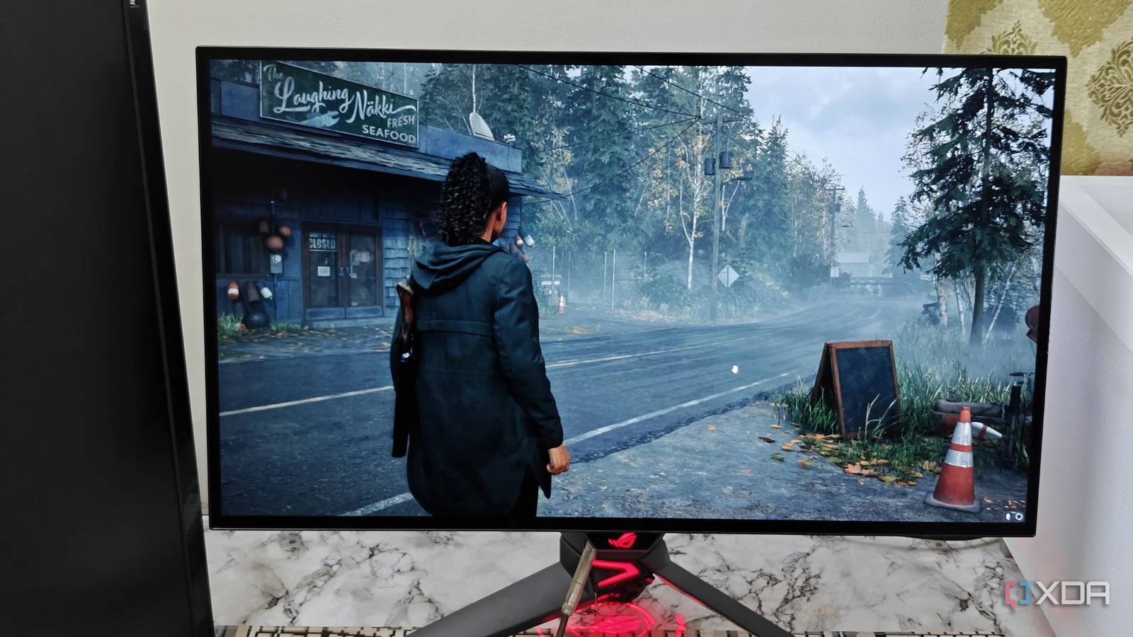 An image showing the  Asus ROG PG27AQDM monitor displaying a screenshot from Alan Wake 2.