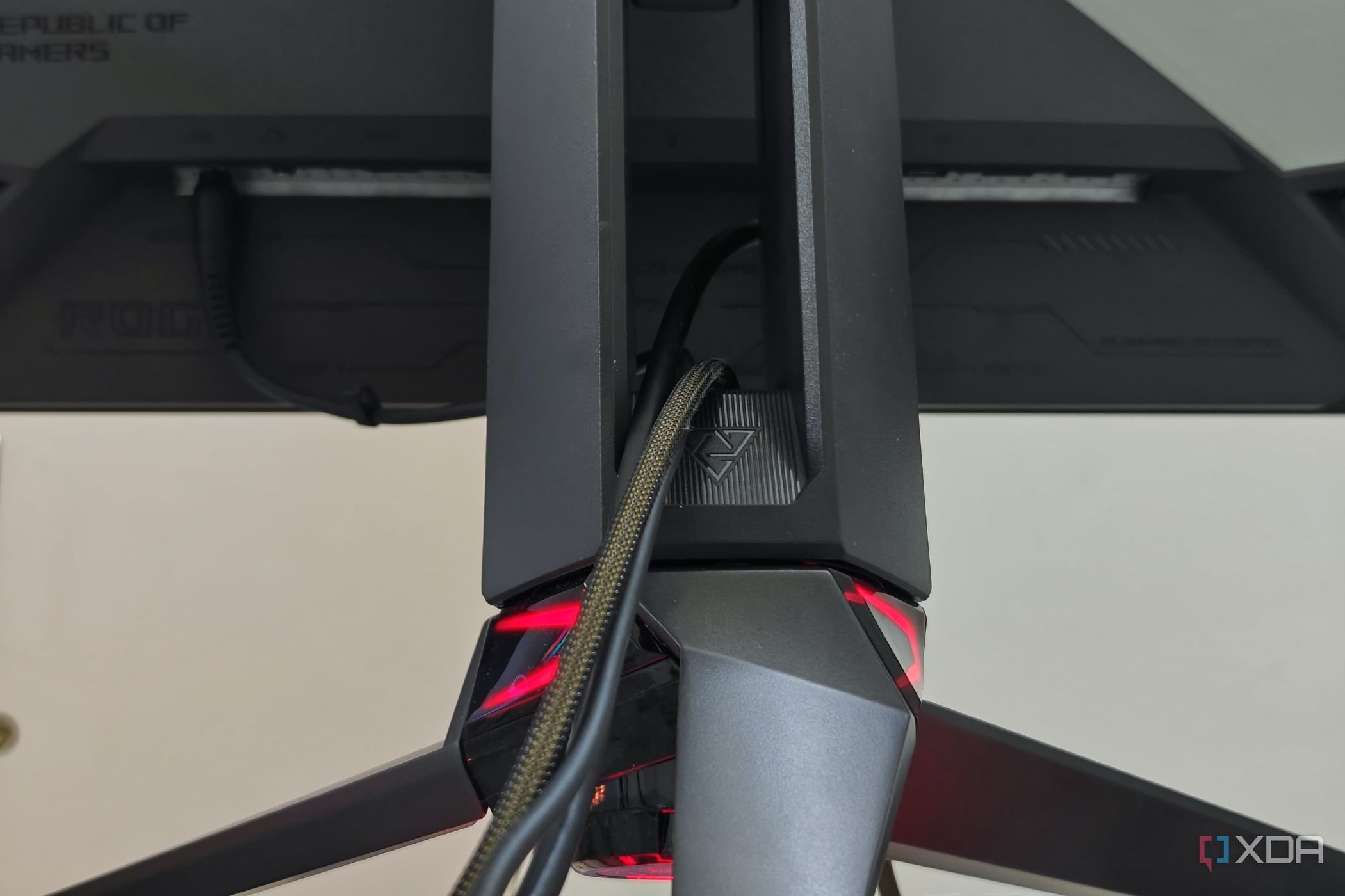 An image showing the tripod stand of the Asus ROG PG27AQDM with cables routed through it.