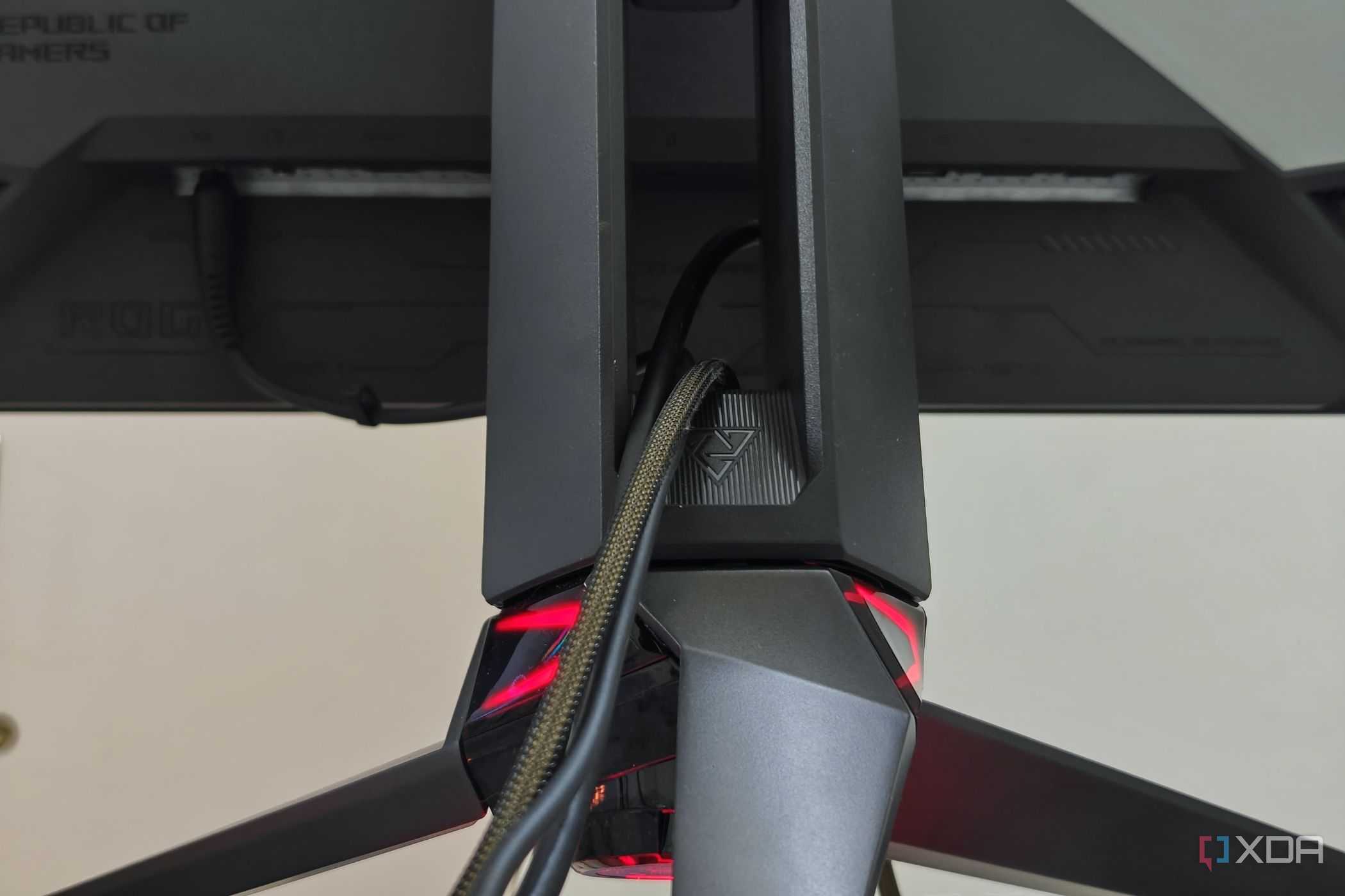 An image showing the tripod stand of the Asus ROG PG27AQDM with cables routed through it.