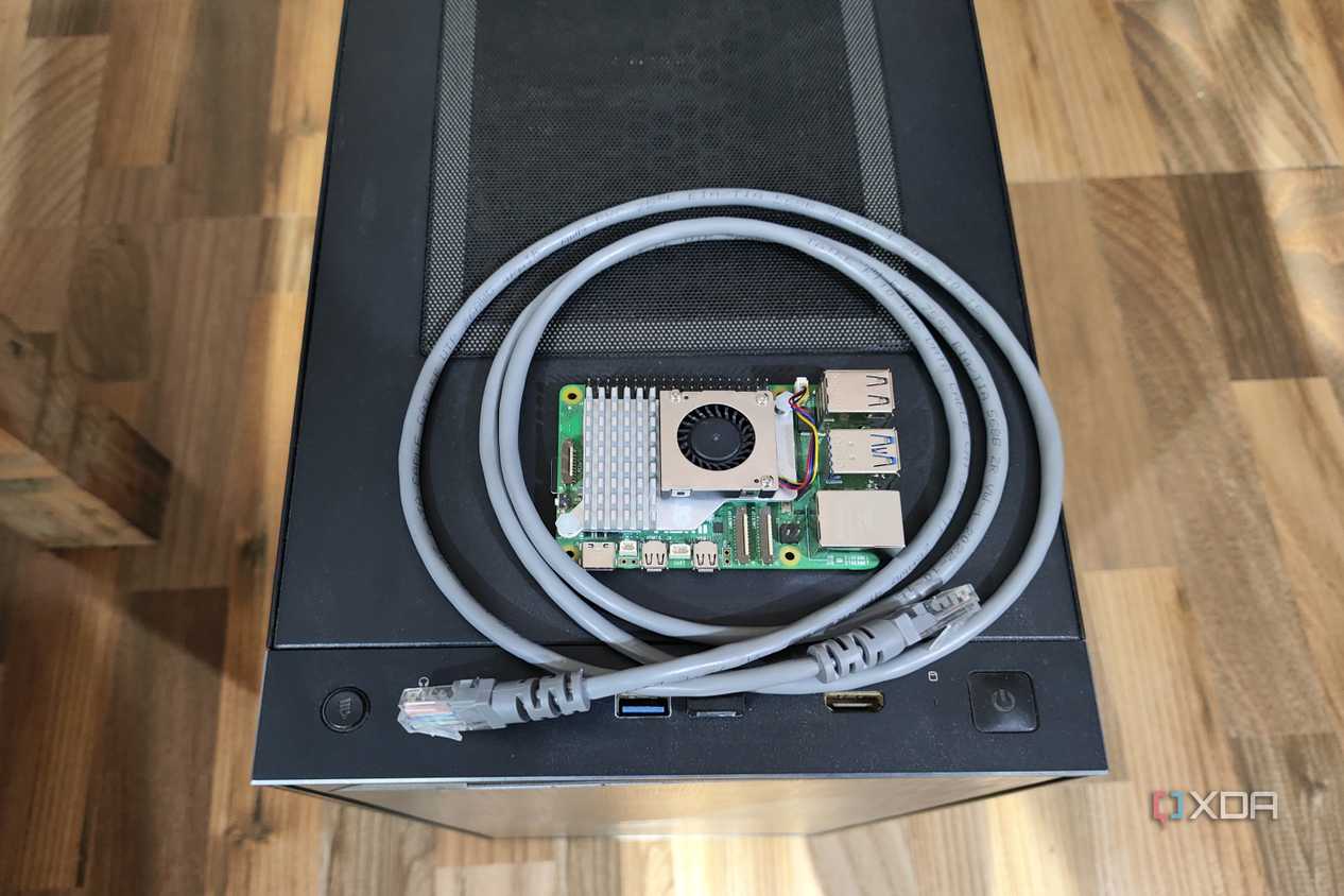 A Raspberry Pi 5 resting on a PC case, with a LAN cable wrapped around it