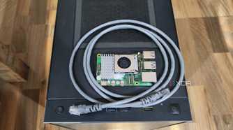 A Raspberry Pi 5 resting on a PC case, with a LAN cable wrapped around it