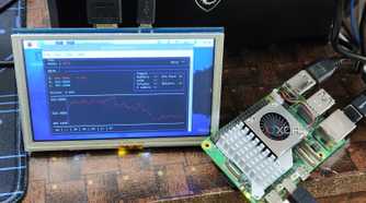 A Raspberry Pi 5 placed next to a portable screen running Tickrs