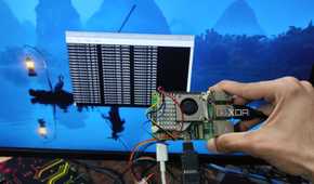 A person holding a Raspberry Pi 5 with a BME280 sensor attached to it in front of a screen