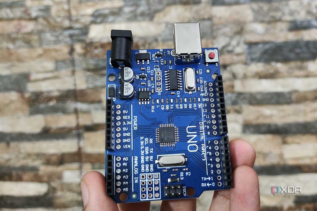 A person holding an Arduino Uno
