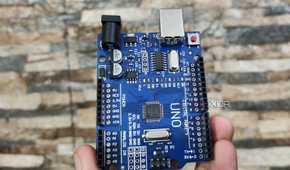 A person holding an Arduino Uno