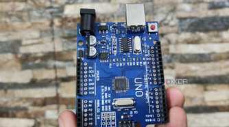 A person holding an Arduino Uno