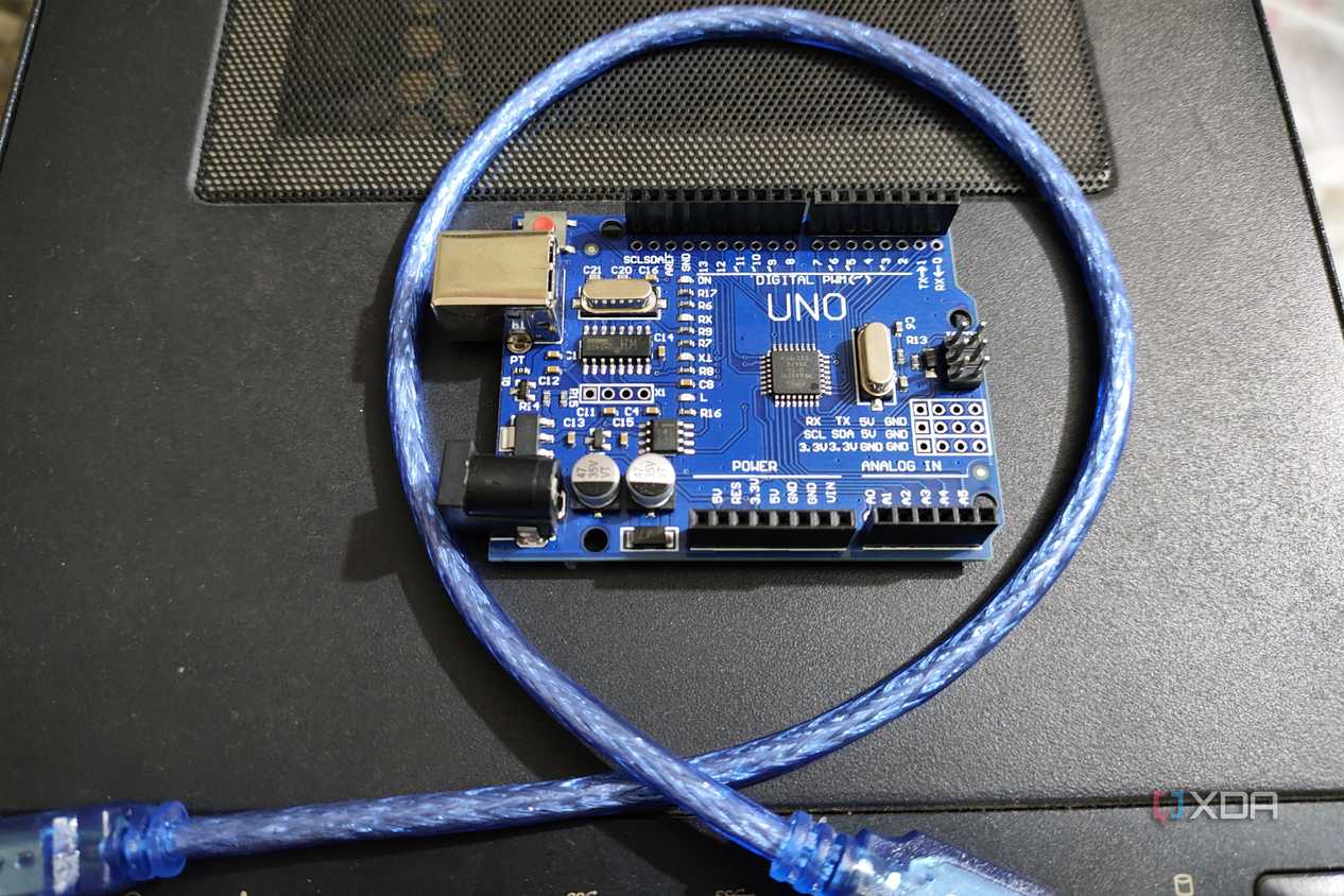 An Arduino Uno resting on a PC case with a cable wrapped around it