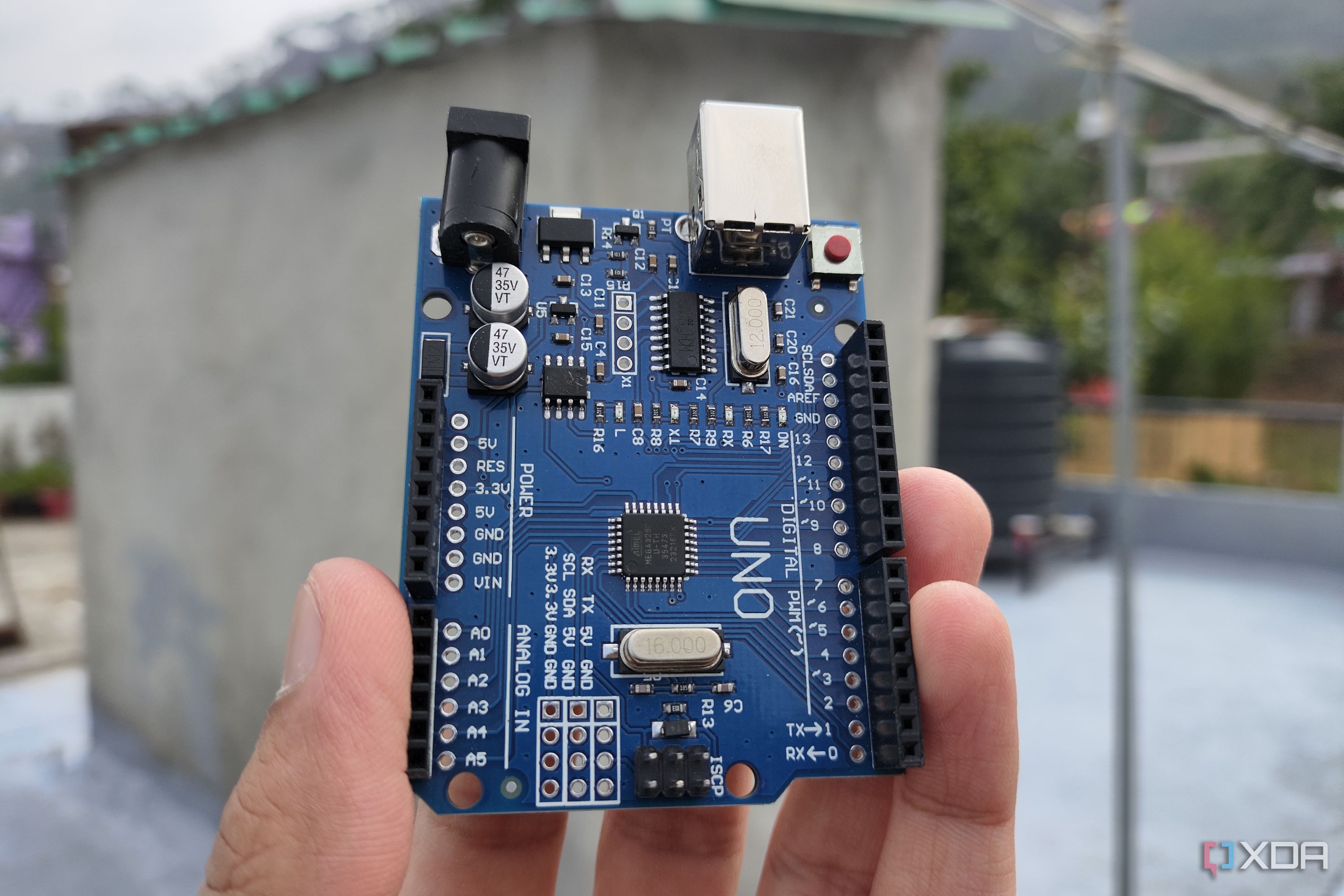 A person holding an Arduino Uno board