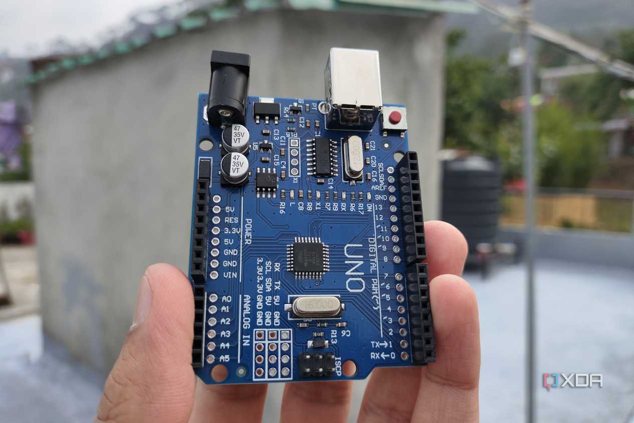 A person holding an Arduino Uno board