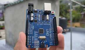 A person holding an Arduino Uno board