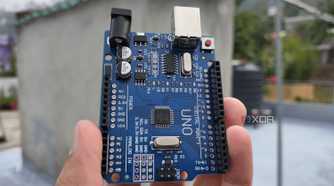A person holding an Arduino Uno board