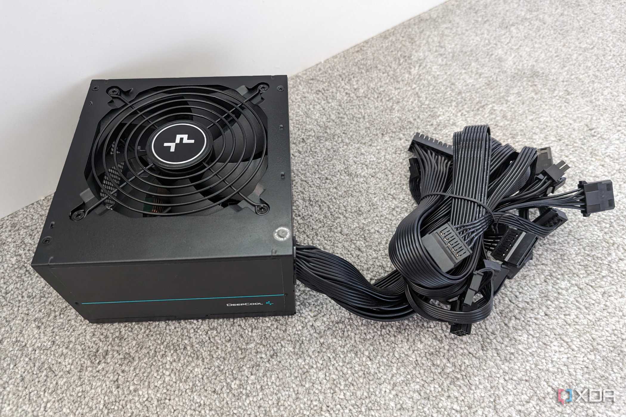 The underside of a DeepCool PM500D power supply with non-modular cables bundled together