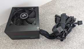 The underside of a DeepCool PM500D power supply with non-modular cables bundled together