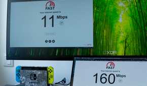 Two computers running a speed test on fast.com. One of the computers, the Geekom A8, only reaches speeds of 11Mbps, while the other is at 160Mbps.