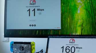 Two computers running a speed test on fast.com. One of the computers, the Geekom A8, only reaches speeds of 11Mbps, while the other is at 160Mbps.
