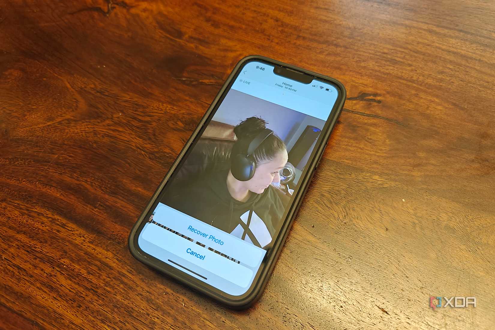 An iPhone on a table showing a photo of a woman wearing headphones and Recover Photo at the bottom.