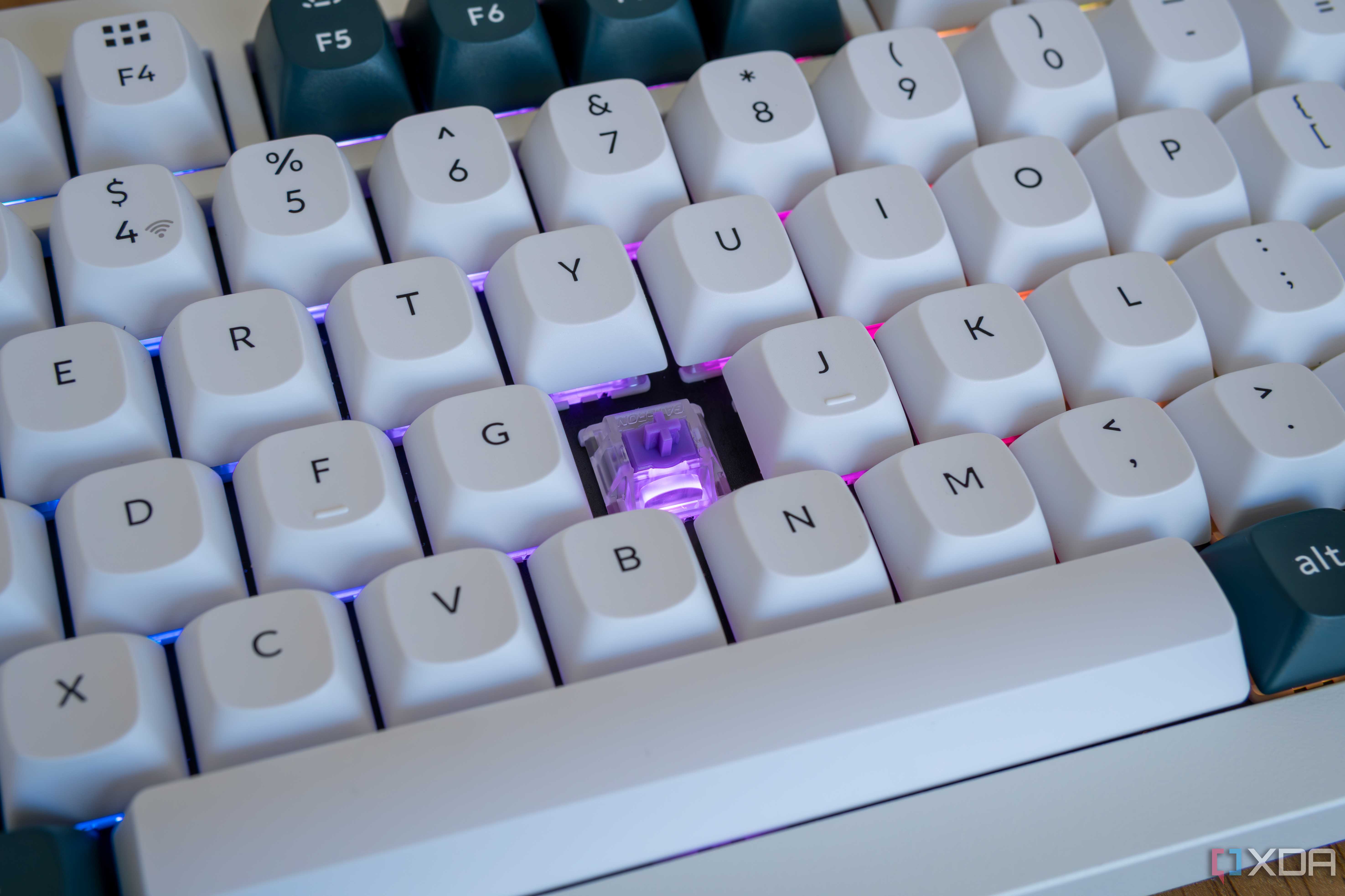 Cloe-up of the Keychron Q1 HE with one of the keycaps removed and a purple light on the exposed switch
