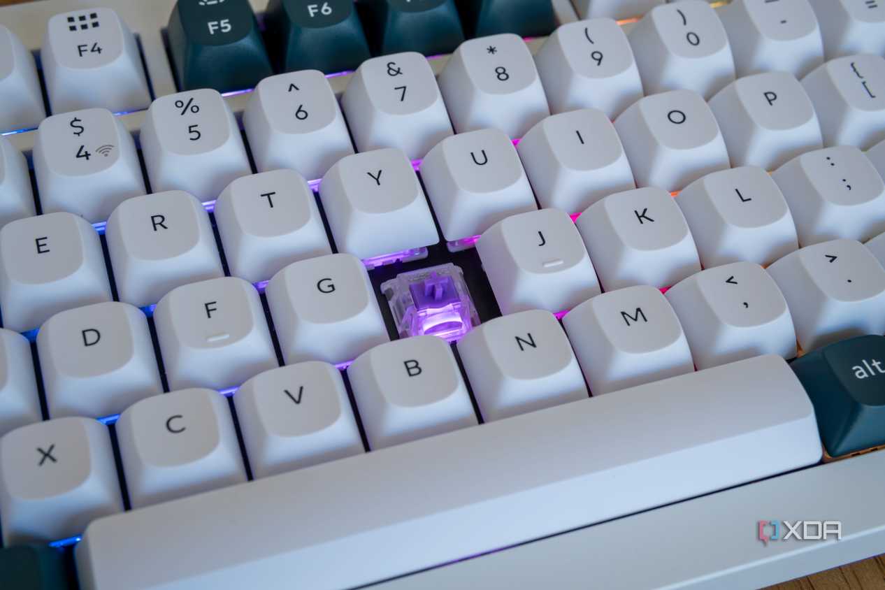 Cloe-up of the Keychron Q1 HE with one of the keycaps removed and a purple light on the exposed switch