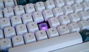 Cloe-up of the Keychron Q1 HE with one of the keycaps removed and a purple light on the exposed switch