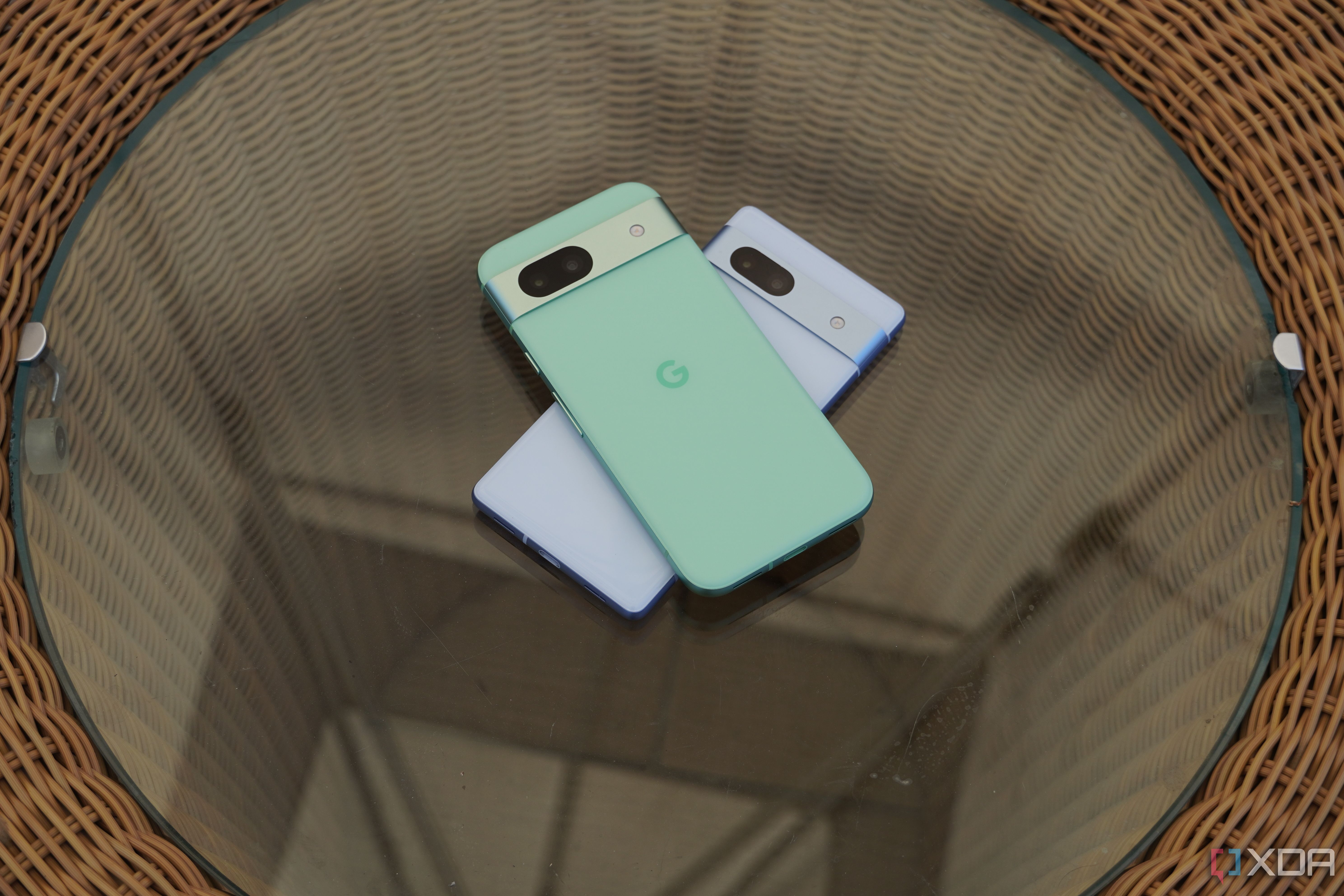 The Pixel 8a and Pixel 7a stacked on a glass table.