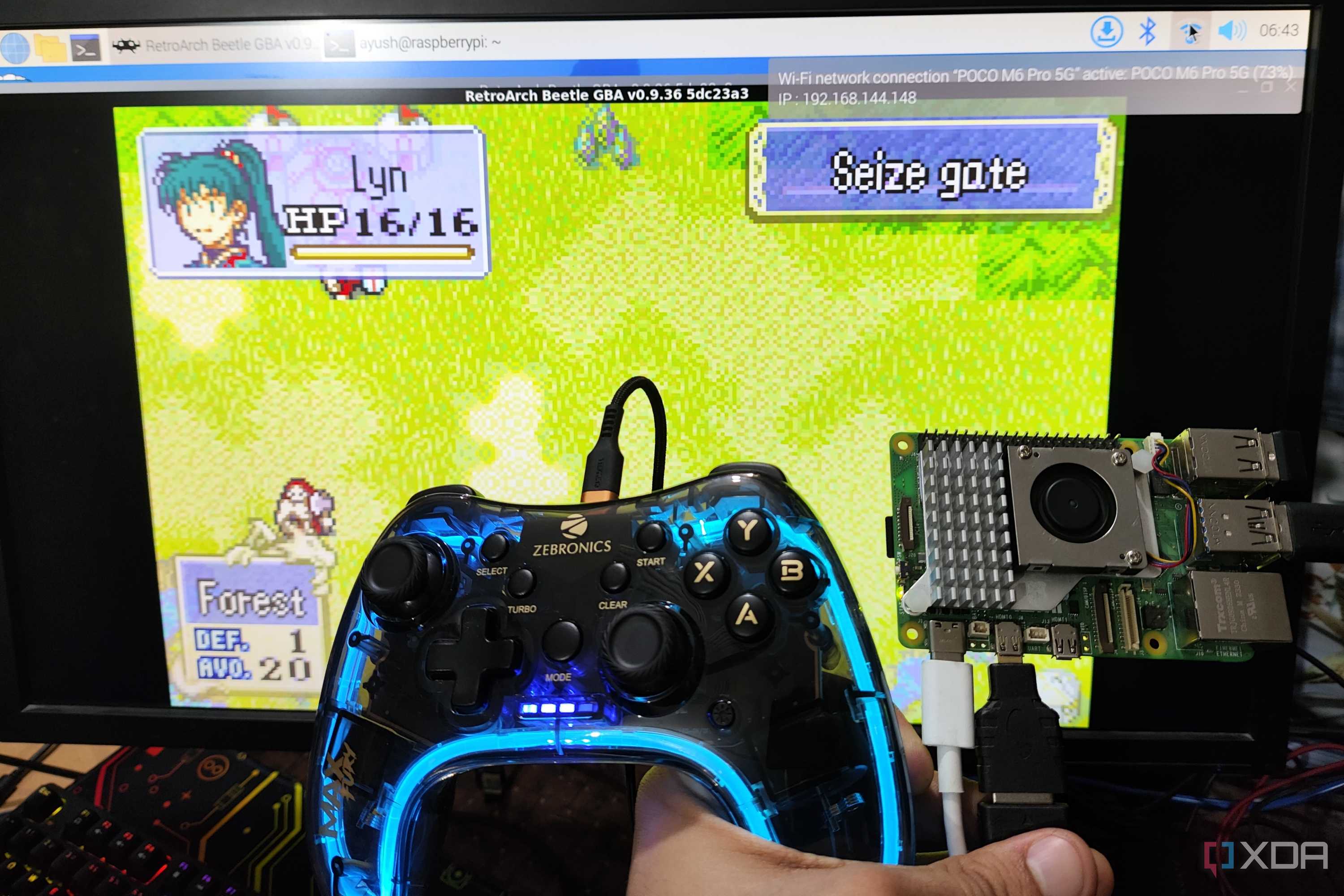 A Raspberry Pi 5 and a controller held in front of a PC screen