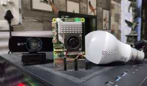 A Raspberry Pi 5 placed next to a webcam and a bulb