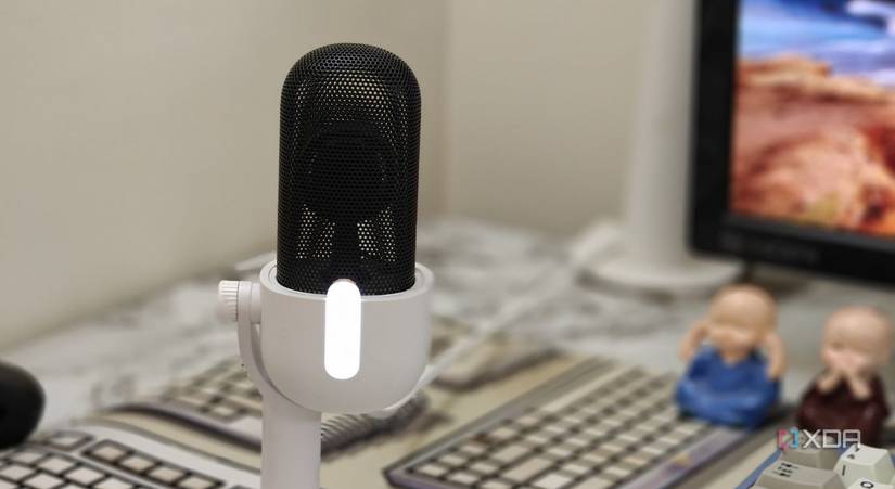 An image showing the Wave Neo microphone kept on a desk next to a monitor.