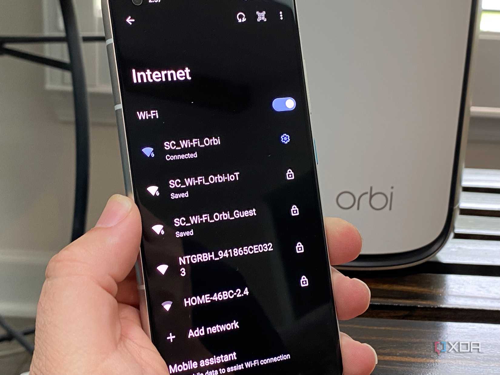 Netgear router with IoT, Guest, and standard Wi-Fi shown on an Android phone