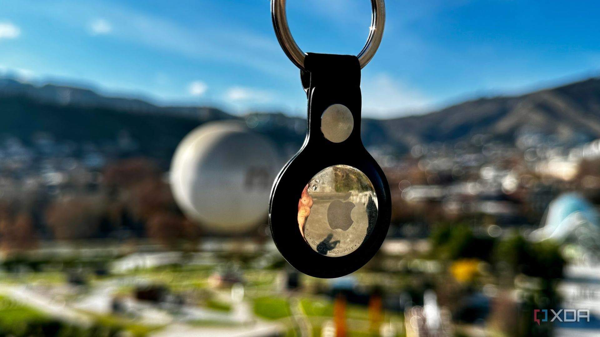 floating Apple AirTag keychain with greenery in the background