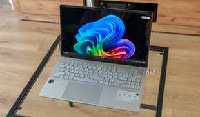 Angled view of the Asus Vivobook S 15 showinf the Windows 11 desktop on a glass table