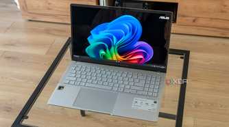 Angled view of the Asus Vivobook S 15 showinf the Windows 11 desktop on a glass table