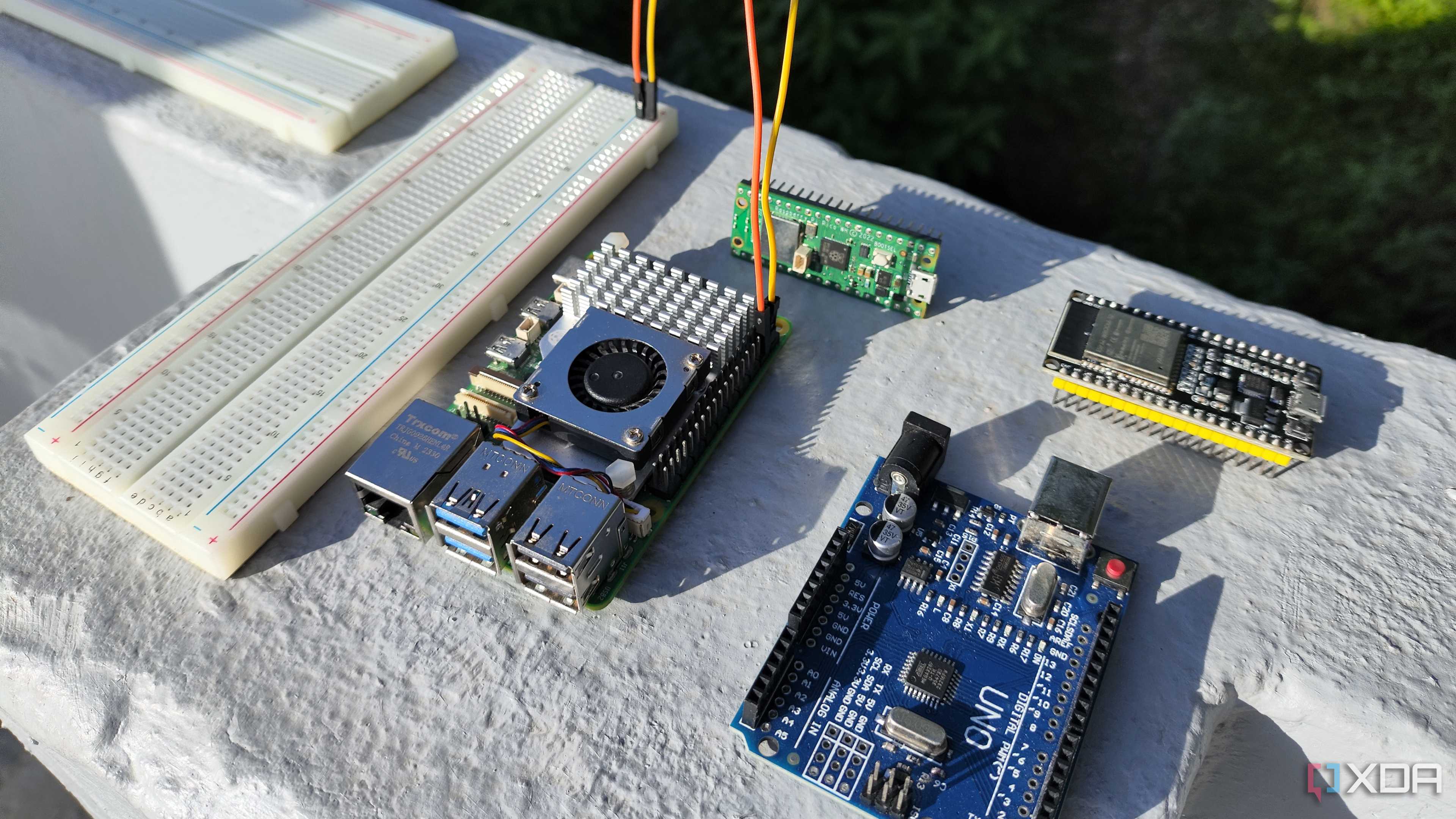A breadboard connected to a Raspberry Pi 5, with microcontrollers lying around them