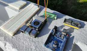 A breadboard connected to a Raspberry Pi 5, with microcontrollers lying around them
