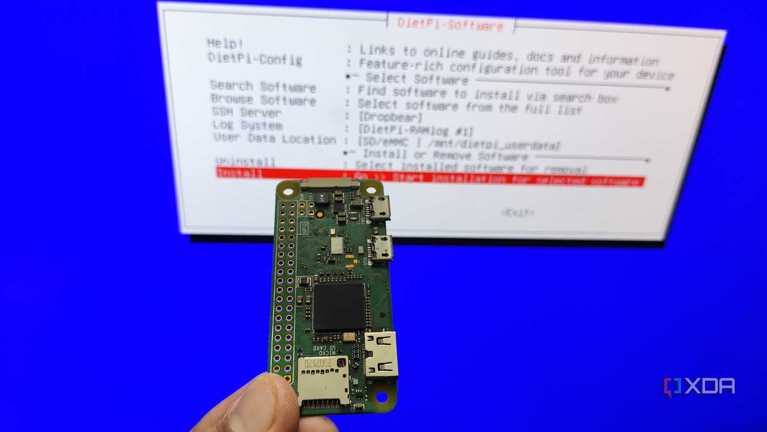A person holding a Raspberry Pi Zero in front of the DietPi installation wizard