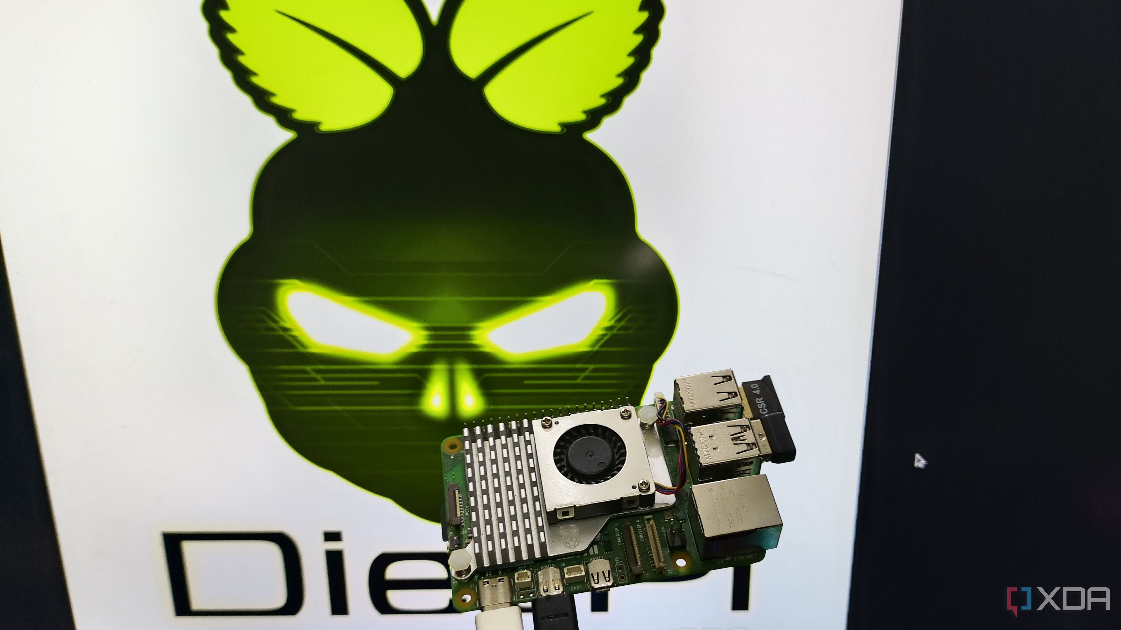 A person holding a Raspberry Pi 5 in front of a monitor displaying the DietPi LXDE desktop environment