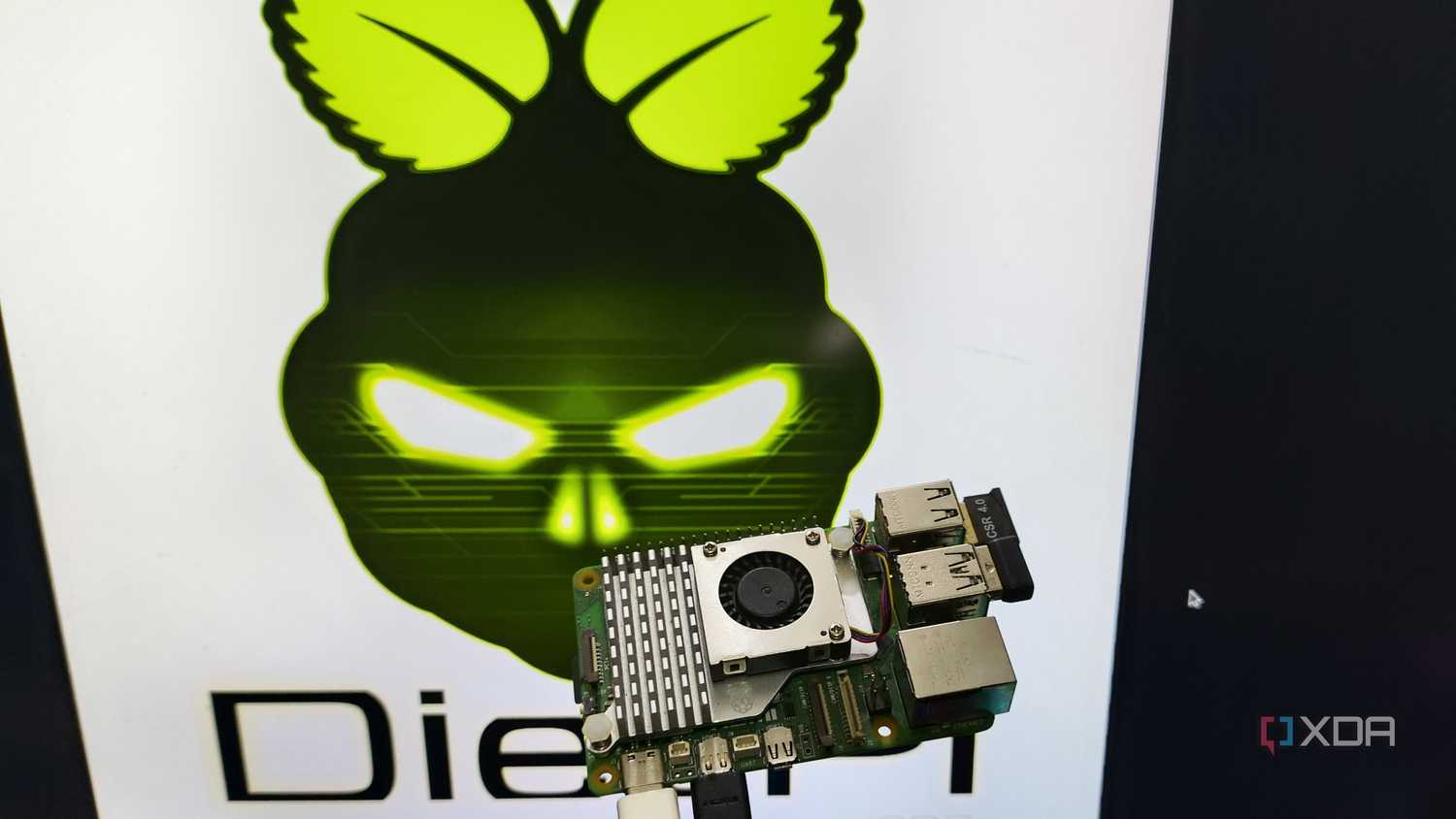 A person holding a Raspberry Pi 5 in front of a monitor displaying the DietPi LXDE desktop environment
