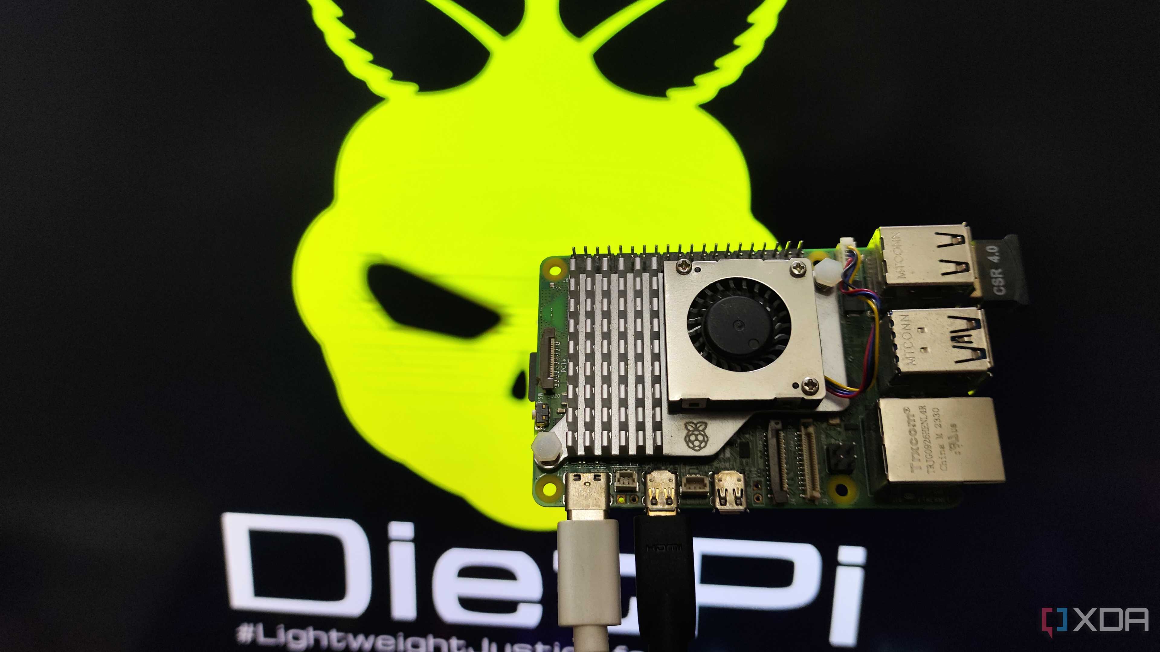 A person holding a Raspberry Pi 5 in front of a monitor displaying the DietPi LXDE desktop environment