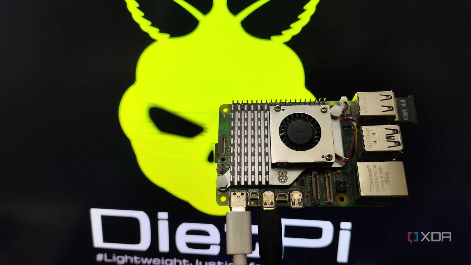 A person holding a Raspberry Pi 5 in front of a monitor displaying the DietPi LXDE desktop environment