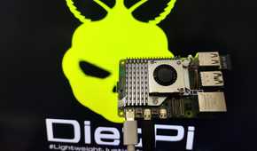 A person holding a Raspberry Pi 5 in front of a monitor displaying the DietPi LXDE desktop environment
